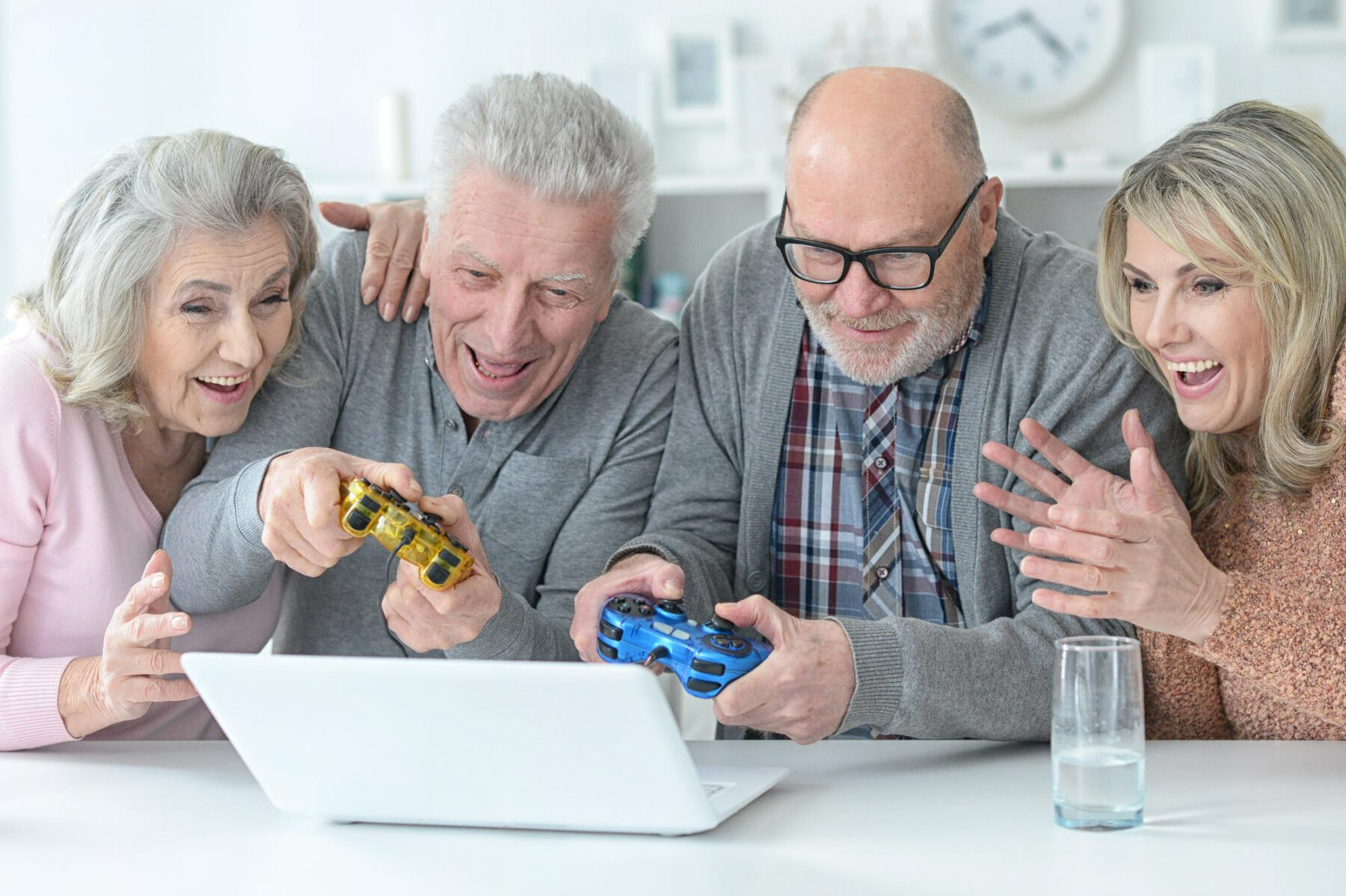 4 personnes âgées jouent à des jeux vidéo devant un ordinateur portable.